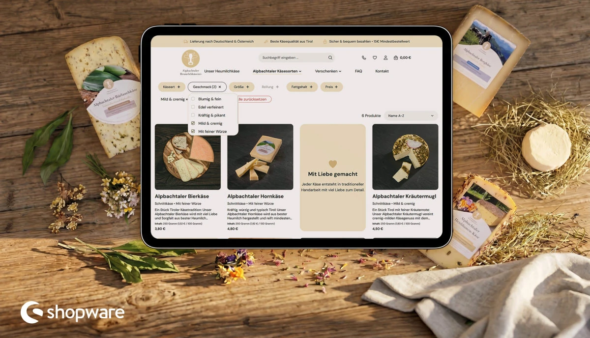 Shopware-6-Onlineshop der Alpbachtaler Heumilchkäserei auf einem Tablet, umgeben von Tiroler Käsesorten.