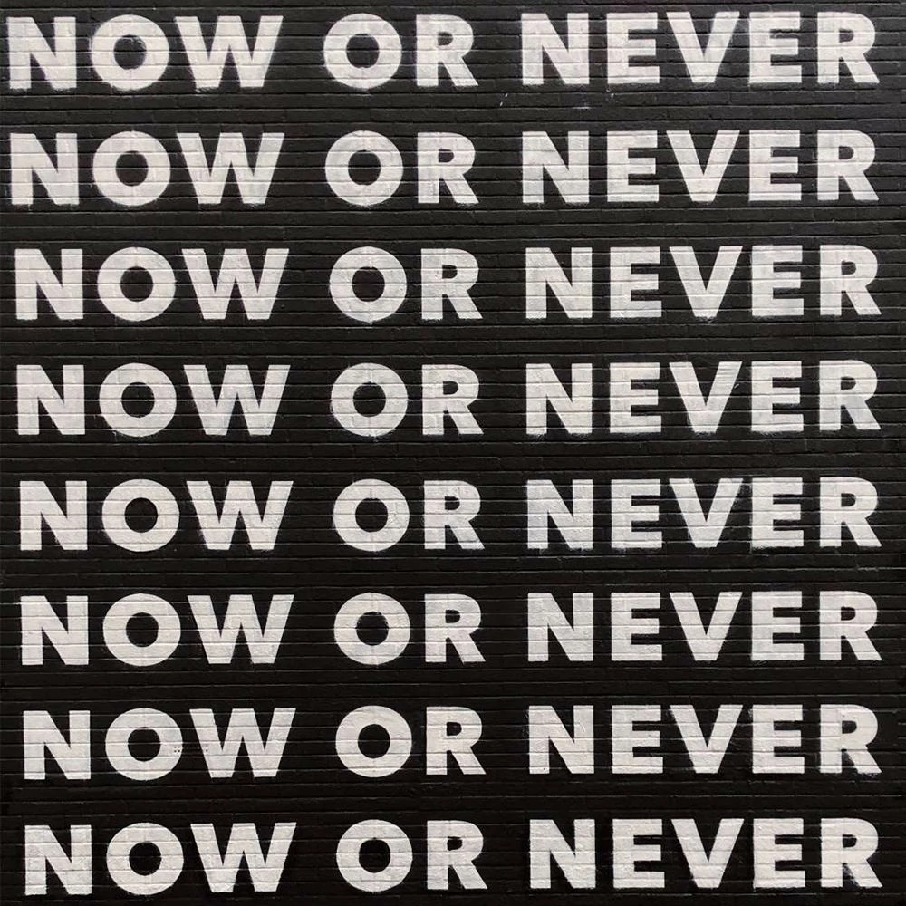 Weiße Schrift auf schwarzem Hintergrund, die acht mal den Satz „Now or never“ in Versalien wiederholt.