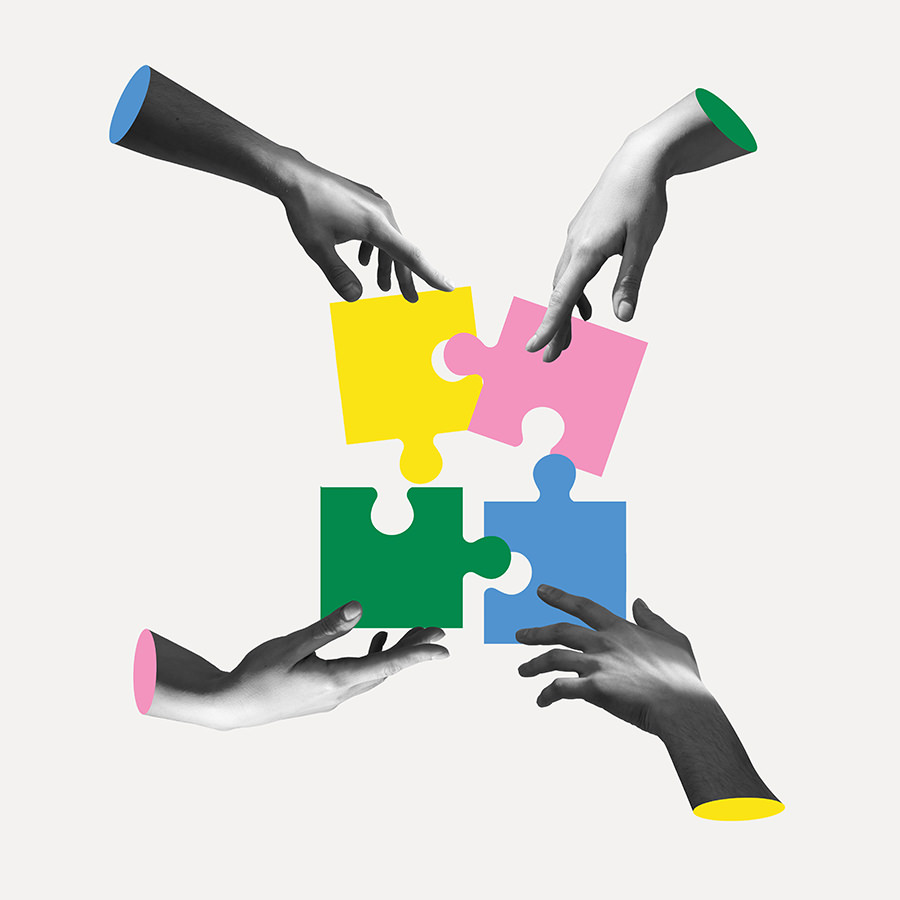 Vier monochrome Hände setzen vier farbige Puzzleteile zusammen.