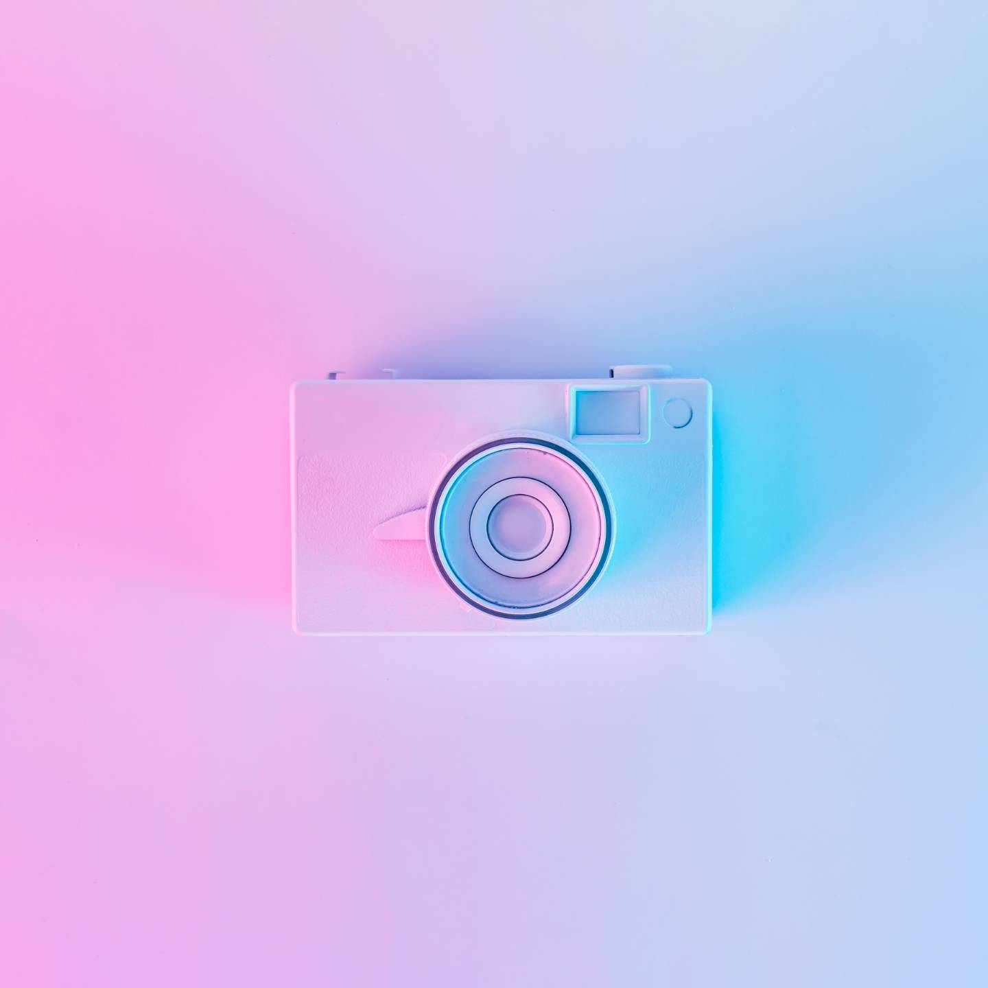 Eine weiße Kamera die von rosanem und blauen Licht bestrahlt wird